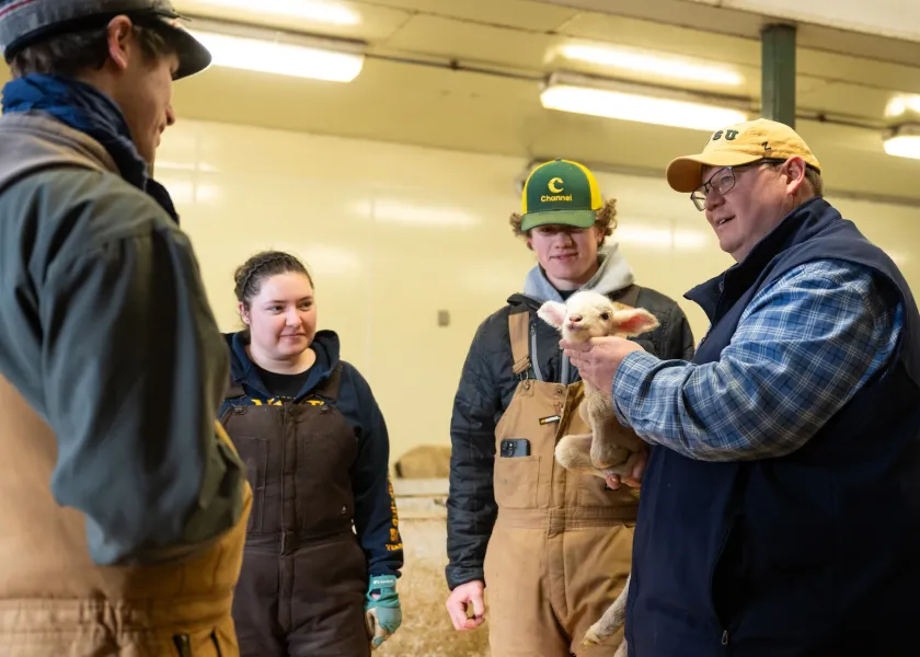 Steven Anderson, manager of NDSU’s Sheep Unit and animal science instructor, holds a lamb in NDSU's Sheep Unit