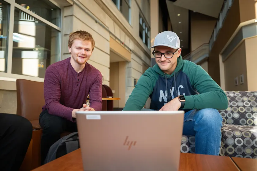 Business students review their coursework on a laptop