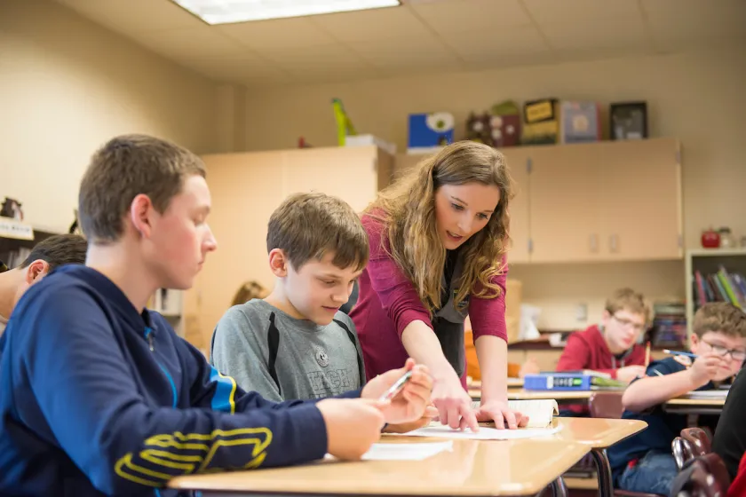 Education student helping young students in the classroom as part of student teaching