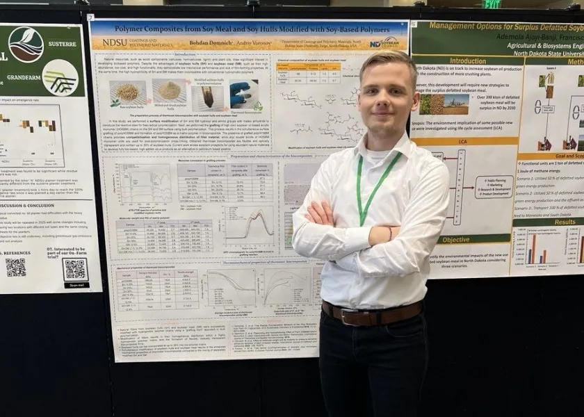 NDSU graduate student standing next to poster board of his work