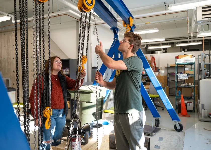 students working in a shop with a hoist