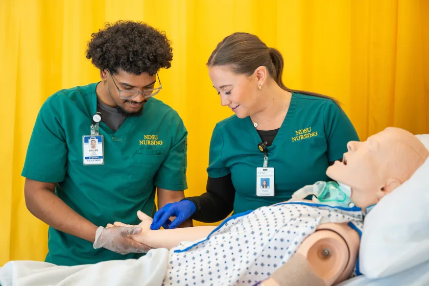 nursing students practicing patient care using a mannequin