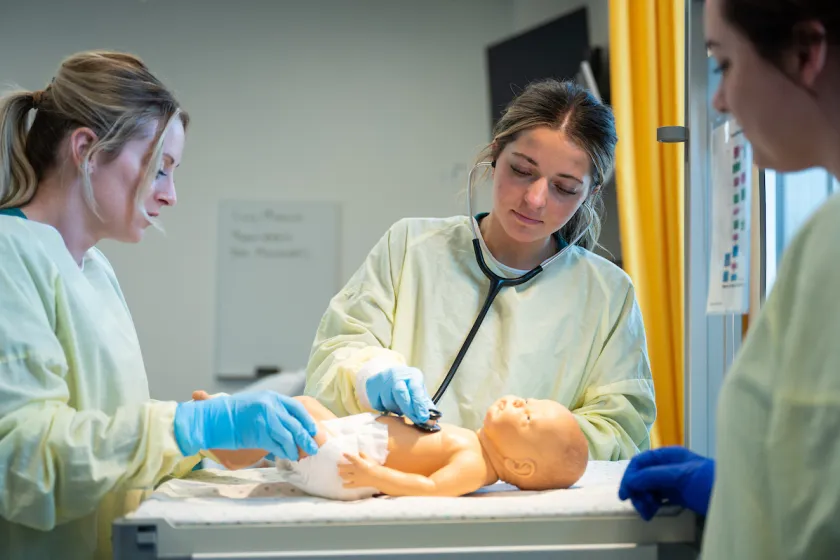 nursing students practicing infant patient care using a mannequin