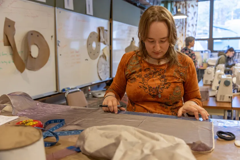 student marking and cutting fabric for theatre costume