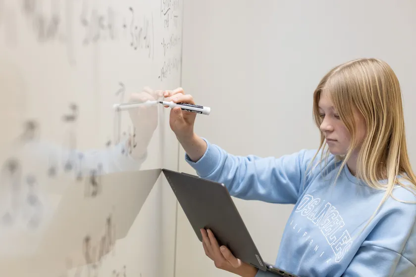 student working on a math equation on a whiteboard