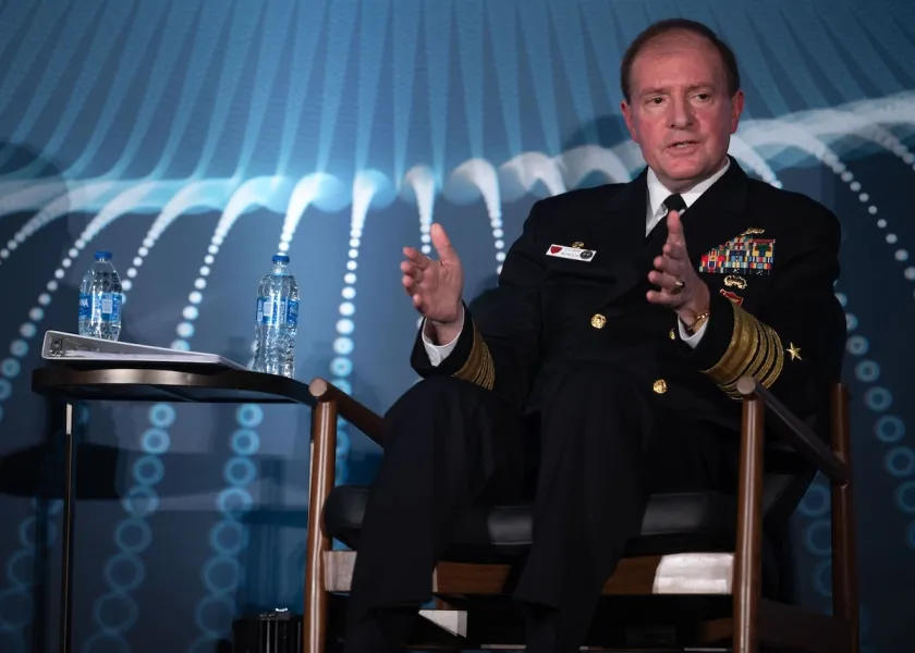 Admiral Stuart Munsch sitting on a stage addressing an audience.