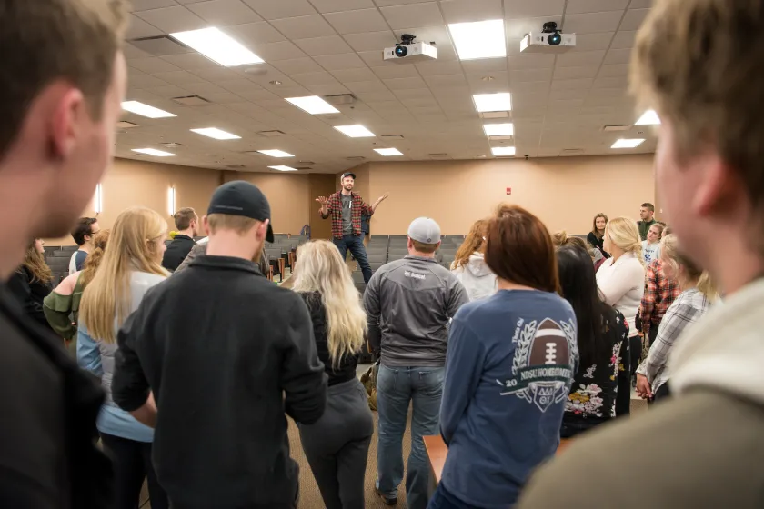 man speaking to a large group of people in a classroom
