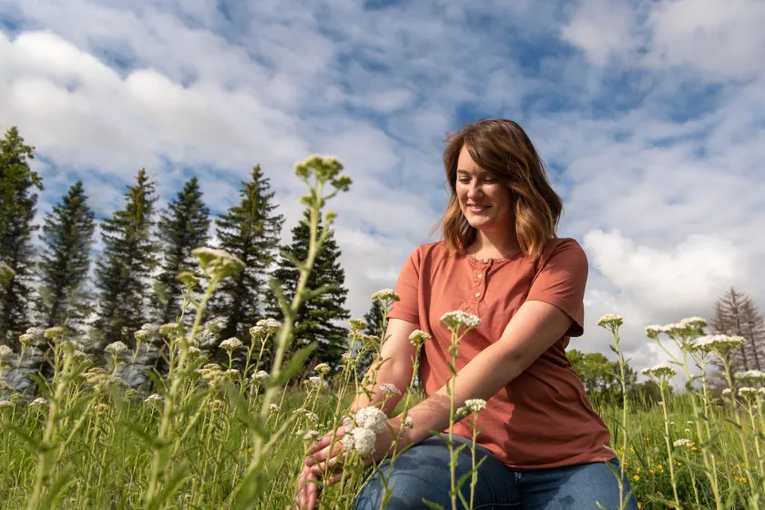 graduate student in a field studying wild flowers