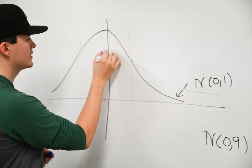 student drawing a graph on a white board