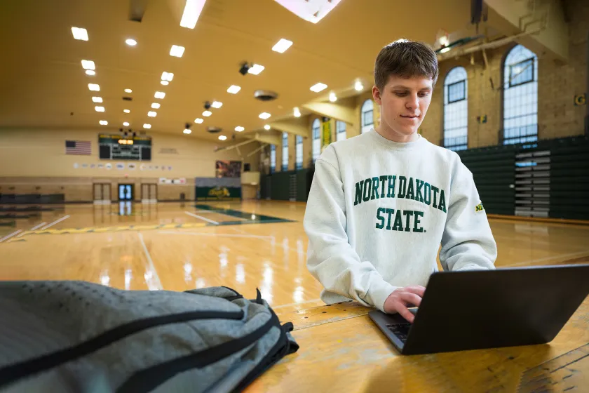 Sport Management student working on a laptop in the Bentson Bunker Fieldhouse