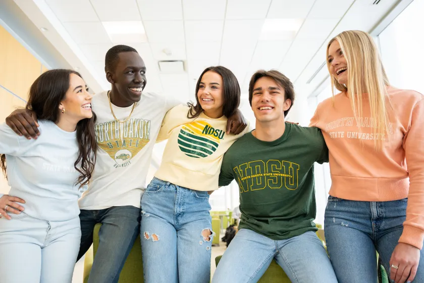 five students talking and laughing while wearing NDSU sweatshirts