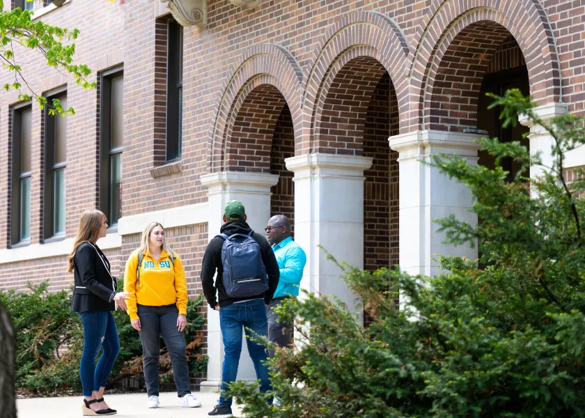 Graduates students and professor standing outside of Minard Hall