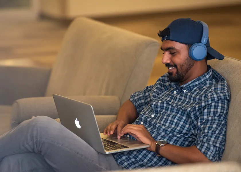 student working on laptop wearing headphones