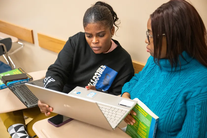 Graduate English students working together on a laptop during class