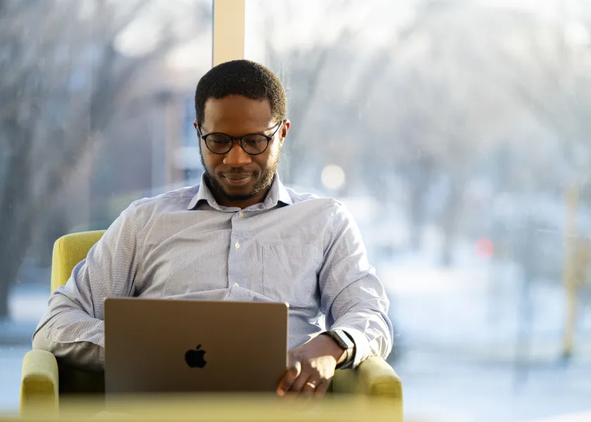 student working on a laptop in front of a window