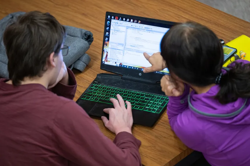 students reviewing code on a laptop screen