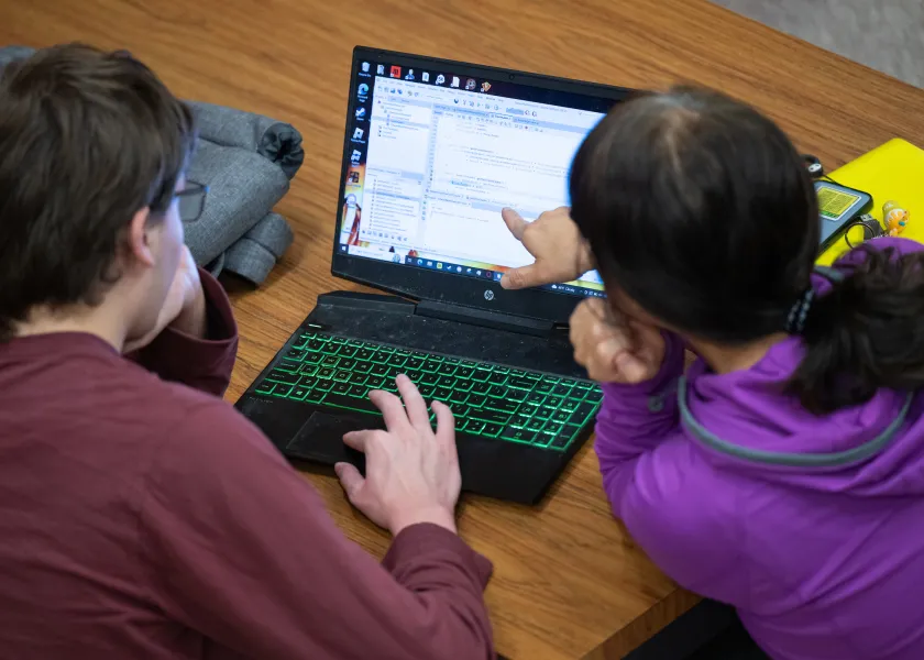 students reviewing code on a laptop screen