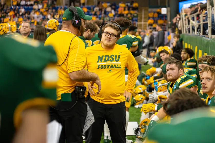 Sport Management students getting hands-on experience with football coaching staff and players during a game