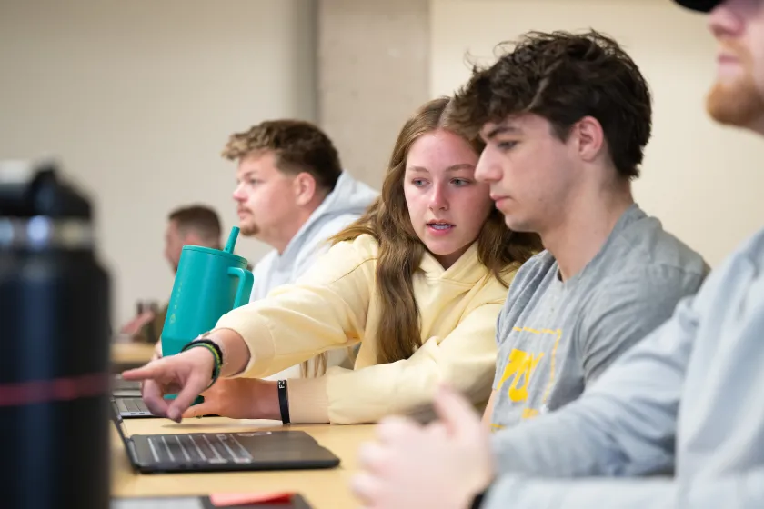 students looking at a laptop screen during class