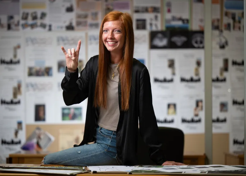 Student smiling confidently at camera with horns up!