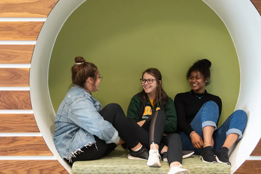 three students in the laundry room of Cater Hall