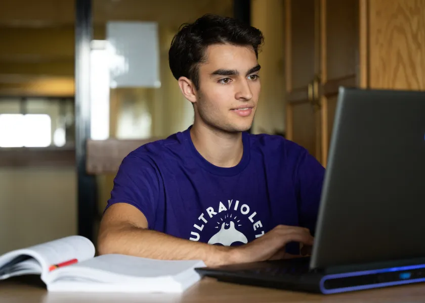 student in his living space on a laptop 