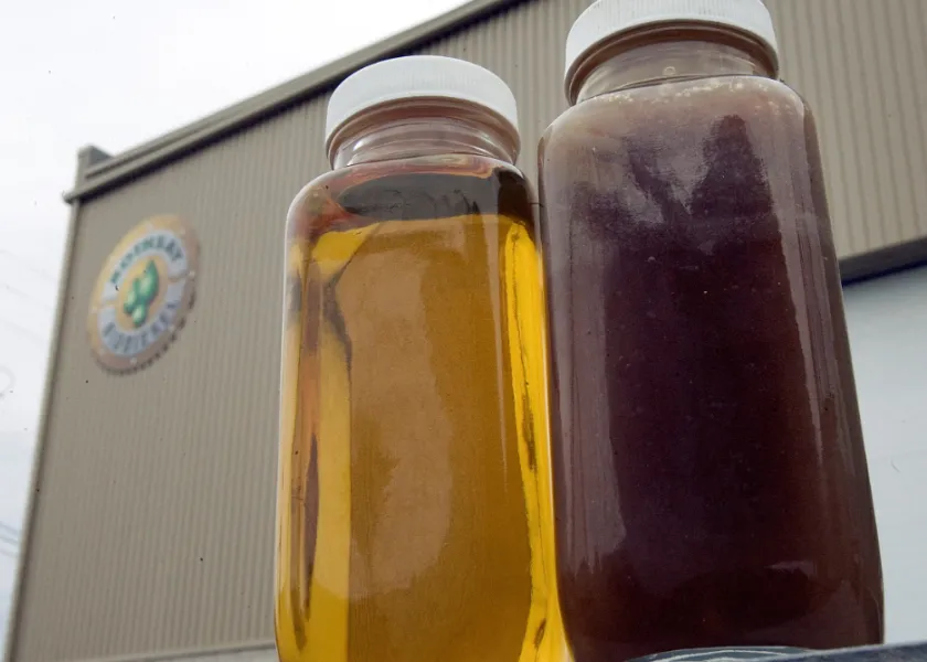 Two bottles of cooking oil sit on a bench