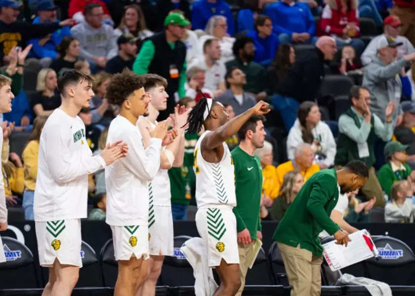 NDSU men's basketball players celebrate on the bench.
