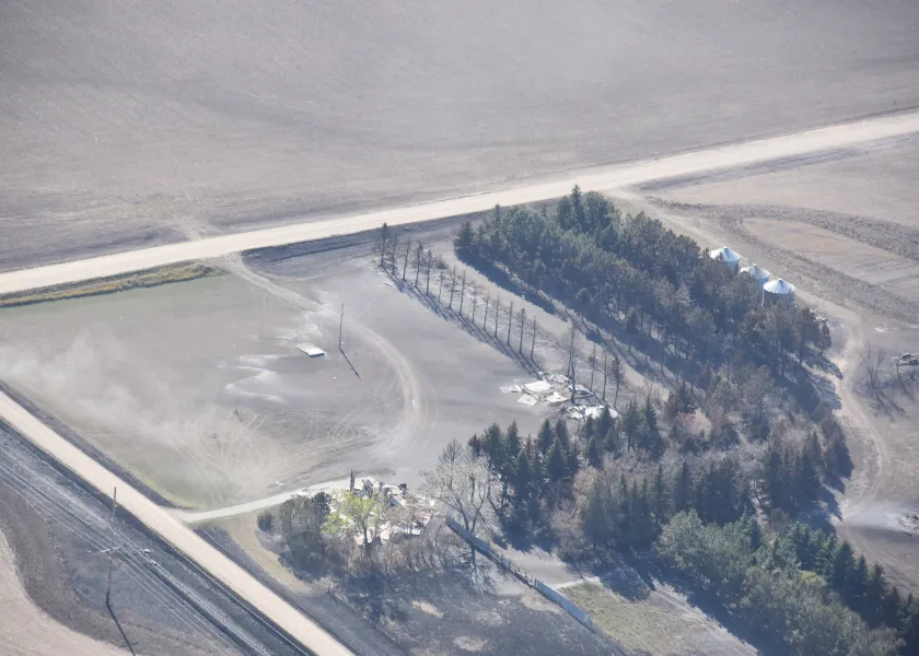 A farmstead showing burnt grass and a burnt row of trees