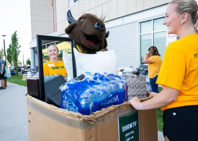 NDSU student and Thundar helping students move in to a residence hall.