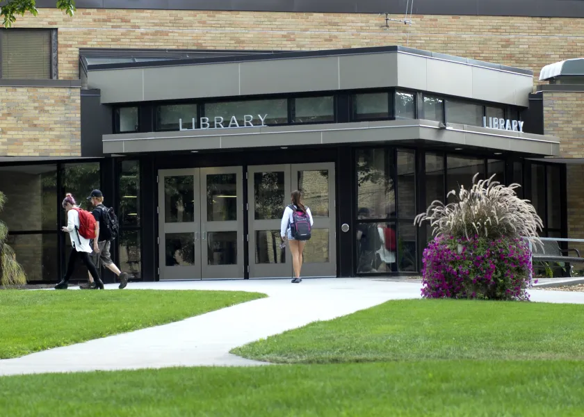 A student walking toward the entrance to the Main Library.