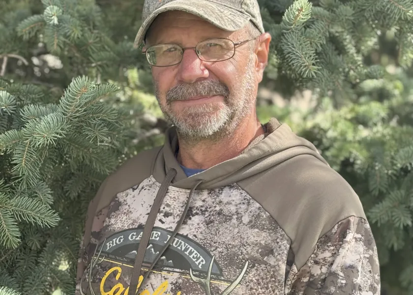 A man in a ballcap and glasses grinning