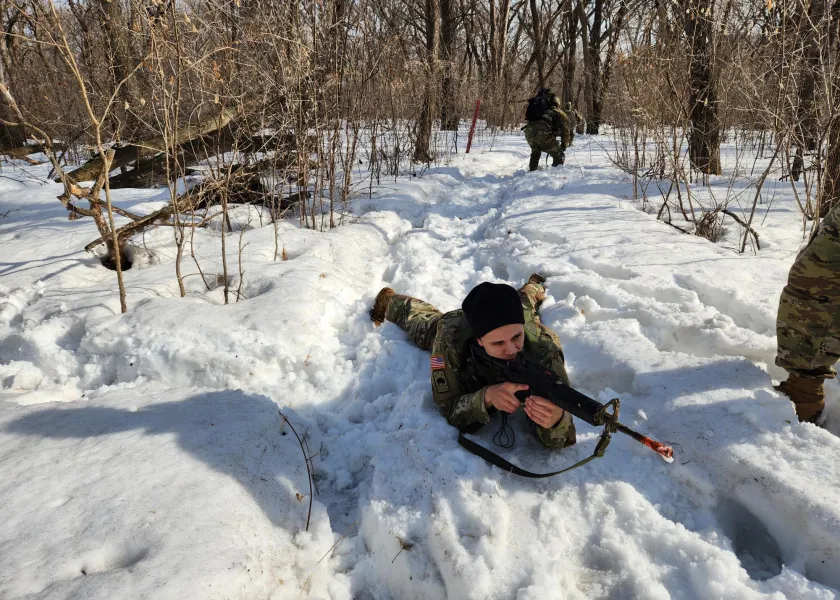 Army ROTC Cadet laying in snow with rifle.