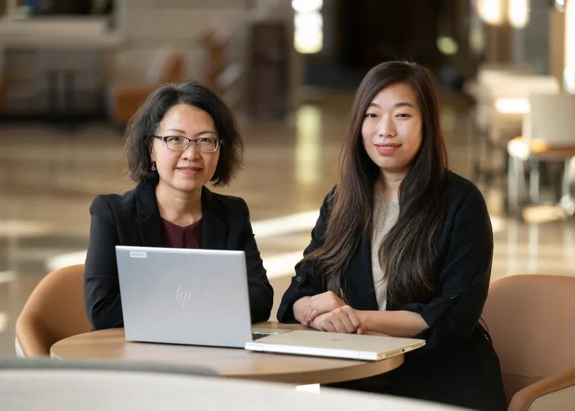 Linlin Chai, associate professor marketing and management and Limin Zhang, associate professor of accounting and information systems, sit at a table with a computer.