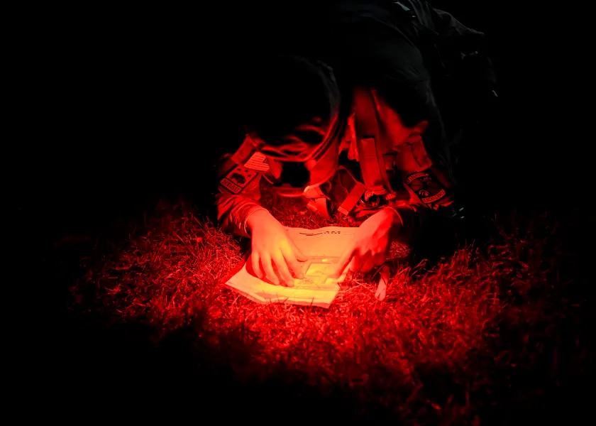 Cadet reading map at night with red lens flashlight
