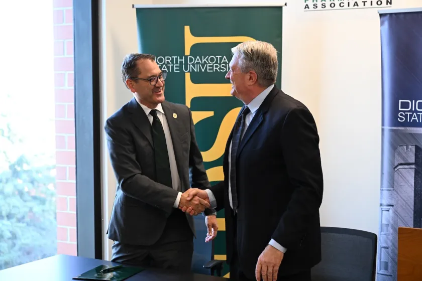 NDSU President Cook and DSU President Molander shake hands after signing MOU