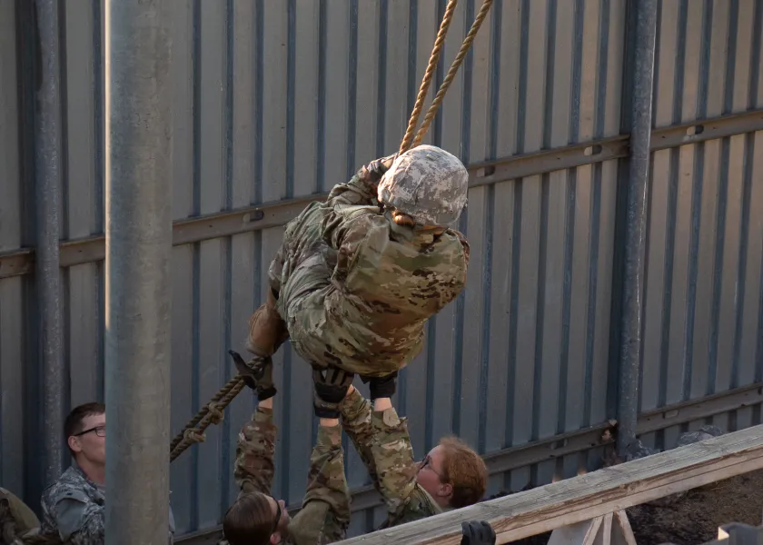 Cadet on obstacle course swinging on rope.
