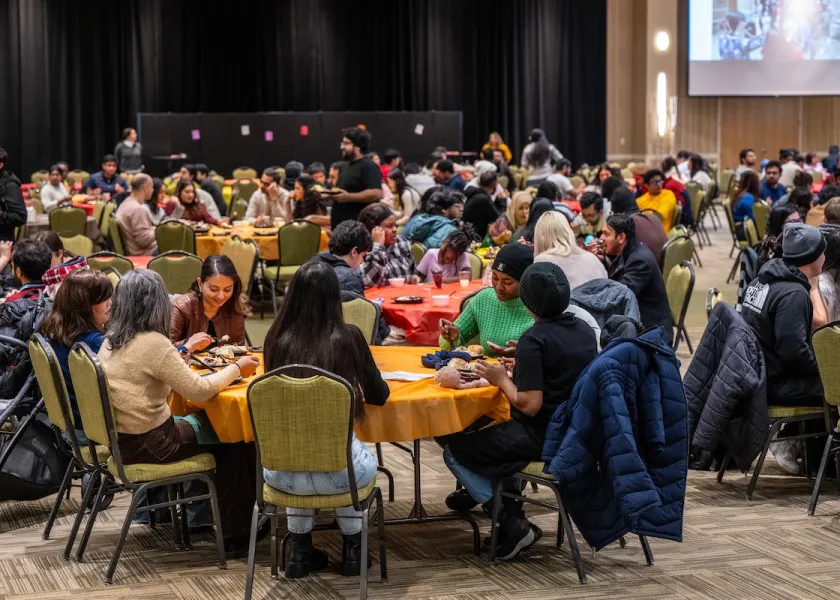 People eating at tables during Friendsgiving event.