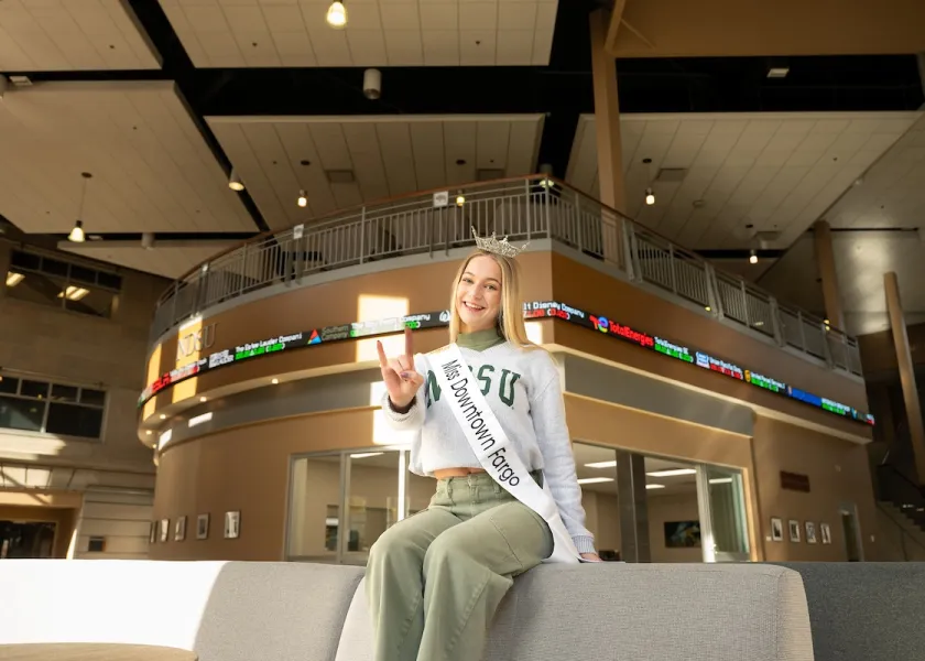 Brynn Olson sitting in Barry Hall wearing a crown and sash.