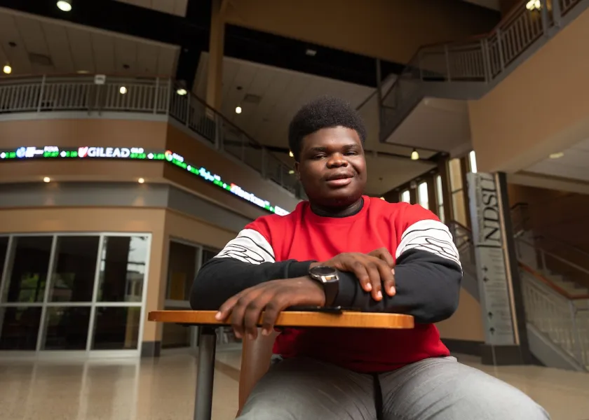 Former NDSU student sitting at a desk.