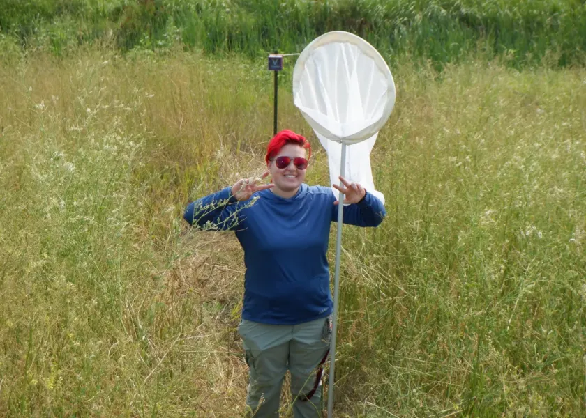 Michaelynne Wilkinson holding a net while standing in green grassy field.