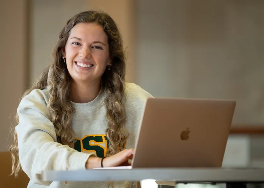 NDSU student Aaliyah Olson posed with a computer at a desk.