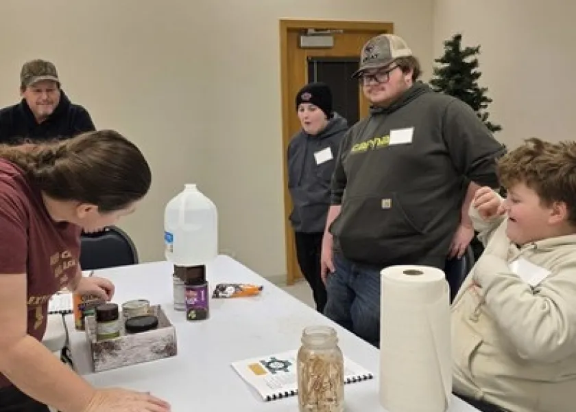 Student's with NDSU's 4-H stand around a table to watch an experiment.