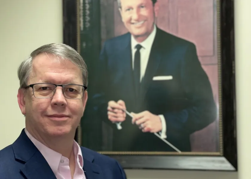 Author Lance Richey stands in front of a painting of Lawrence Welk.