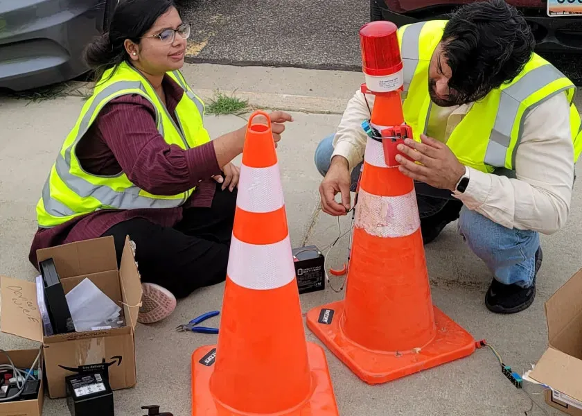 2 students put sensors on highway safety cones as part of a research project