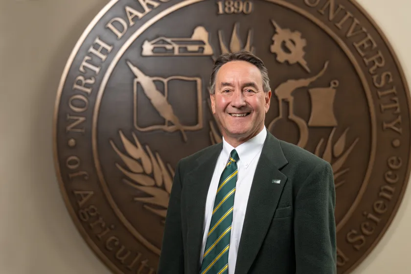 Rick Berg stands in front of the NDSU seal at Old Main