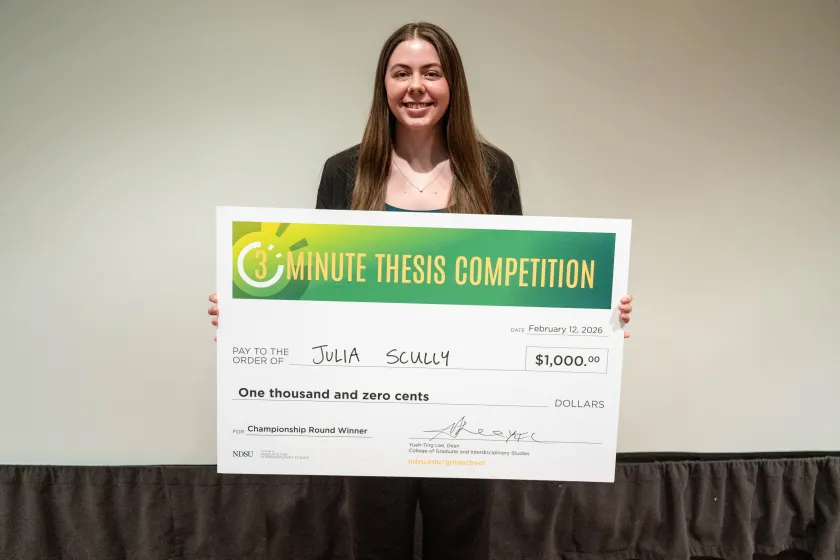 Julia Scully, a master’s student in coatings and polymeric materials, holds a check