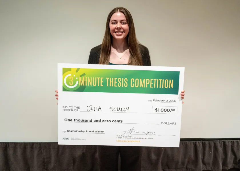 Julia Scully, a master’s student in coatings and polymeric materials, holds a check while posing for a photo.