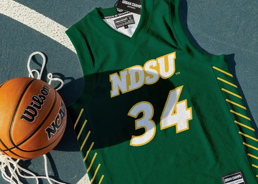 An NDSU basketball jersey lays on a basketball court next to a basketball.