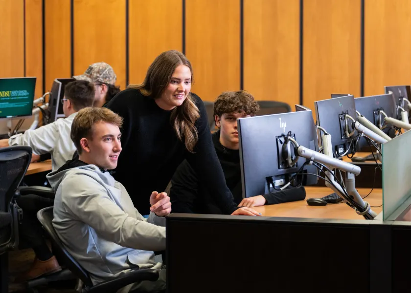 Students gather around a computer in NDSU's Commodity Trading Room in Barry Hall.